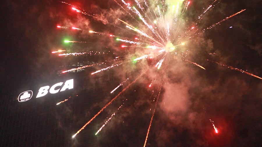 Kembang api menyala di samping logo BCA saat malam pergantian tahun di Bundaran HI, Senin (1/1/2024). (Bloomberg Technoz/Andrean Kristianto)