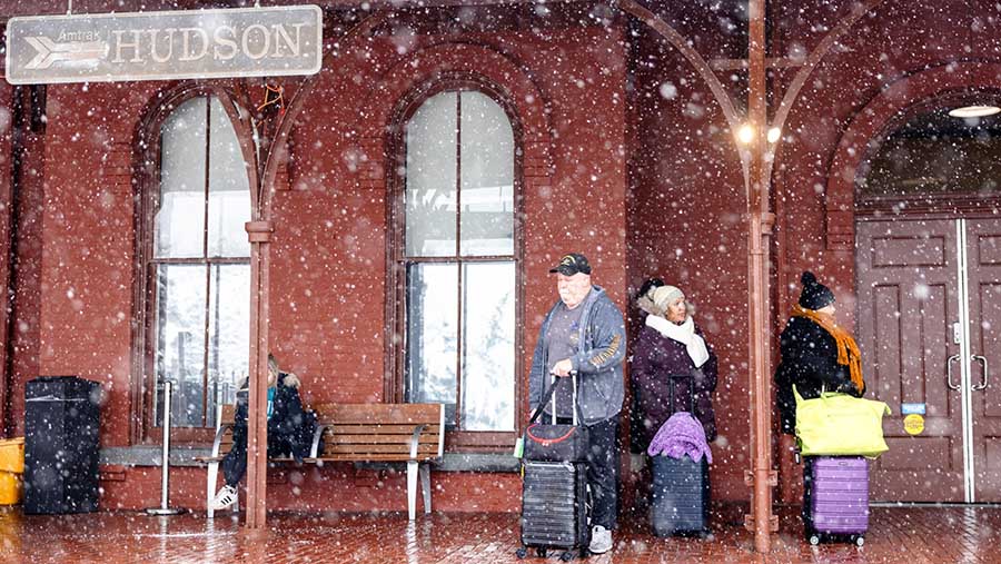Penumpang menunggu kereta Amtrak saat badai di Hudson, New York, AS, Minggu (7/1/2024). (Angus Mordant/Bloomberg)