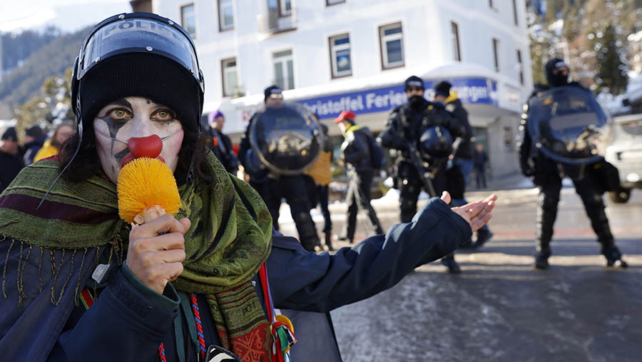 Seorang pengunjuk rasa berpakaian badut demo menentang WEF di Davos, Swiss, Minggu (14/1/2024). (Stefan Wermuth/Bloomberg)