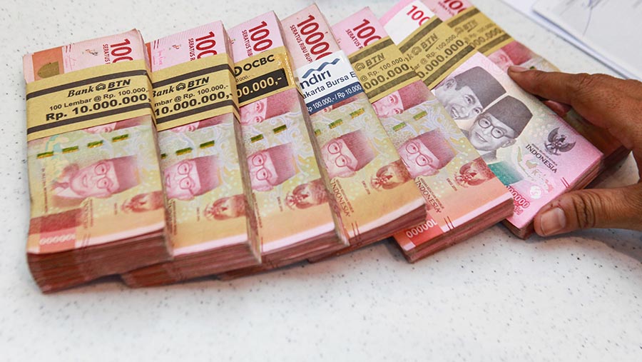 Karyawan merapihkan uang rupiah di salah satu bank di Jakarta, Selasa (16/1/2024). (Bloomberg Technoz/Andrean Kristianto)
