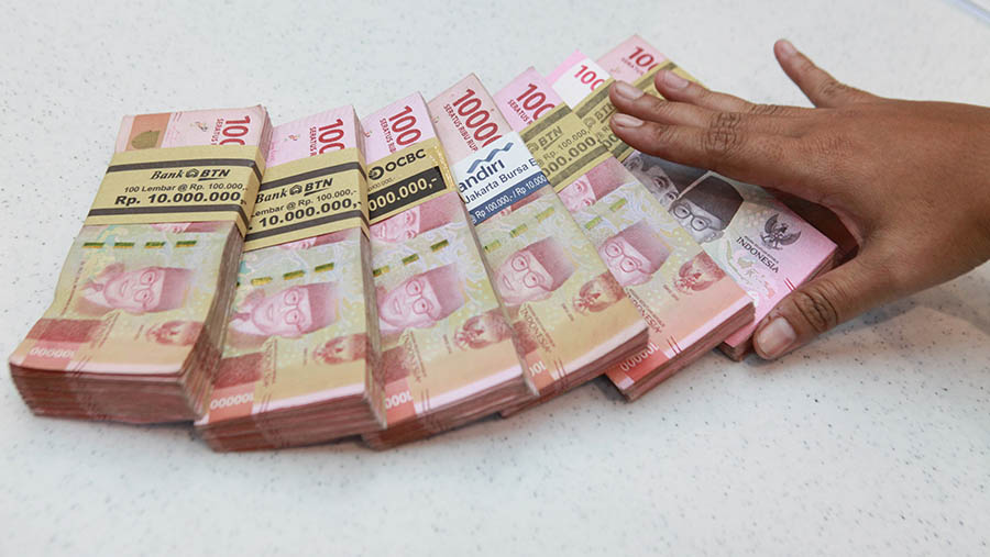 Karyawan merapihkan uang rupiah di salah satu bank di Jakarta, Selasa (16/1/2024). (Bloomberg Technoz/Andrean Kristianto)
