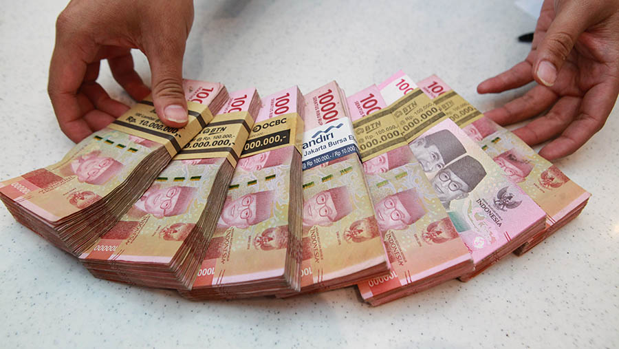 Karyawan merapihkan uang rupiah di salah satu bank di Jakarta, Selasa (16/1/2024). (Bloomberg Technoz/Andrean Kristianto)
