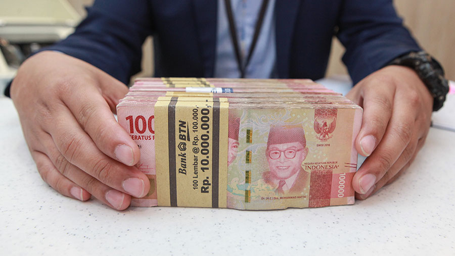 Karyawan merapihkan uang rupiah di salah satu bank di Jakarta, Selasa (16/1/2024). (Bloomberg Technoz/Andrean Kristianto)
