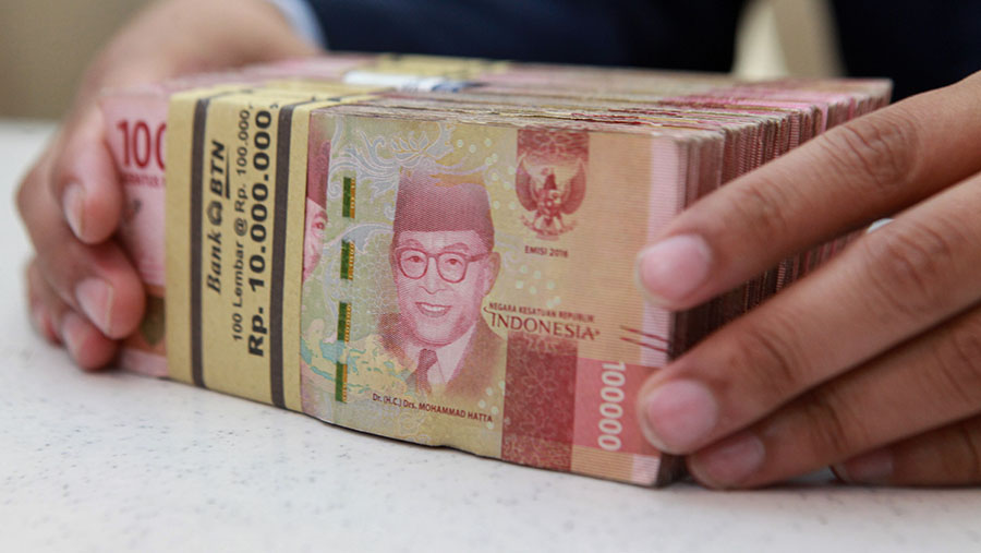 Karyawan merapihkan uang rupiah di salah satu bank di Jakarta, Selasa (16/1/2024). (Bloomberg Technoz/Andrean Kristianto)
