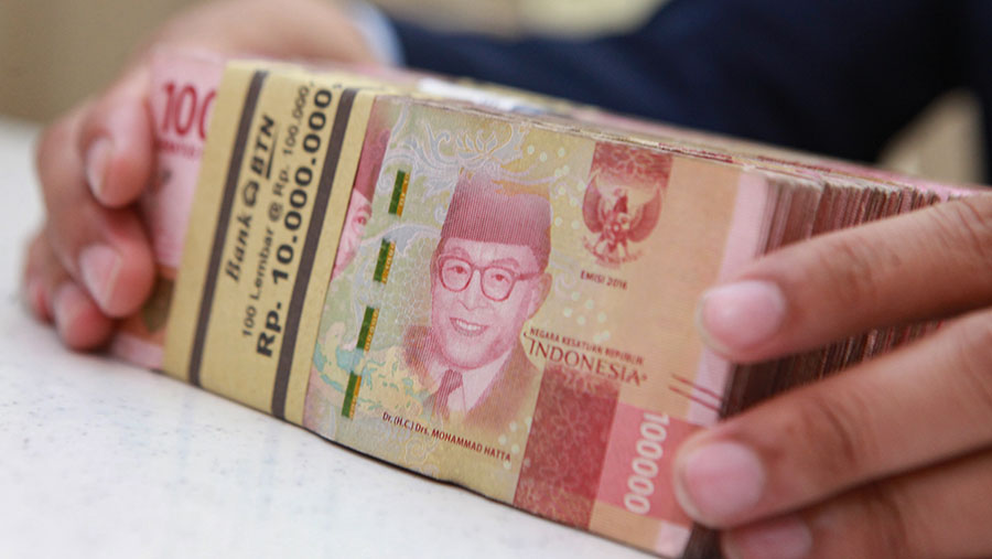 Karyawan merapihkan uang rupiah di salah satu bank di Jakarta, Selasa (16/1/2024). (Bloomberg Technoz/Andrean Kristianto)
