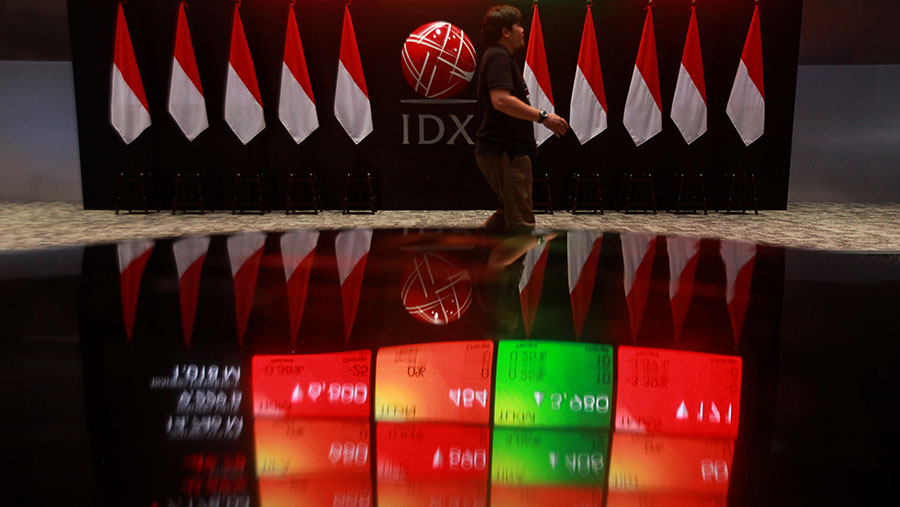 Karyawan melintas di depan layar pergerakan perdagangan saham (IHSG) di Bursa Efek Indonesia (BEI). (Bloomberg Technoz/Andrean Kristianto)