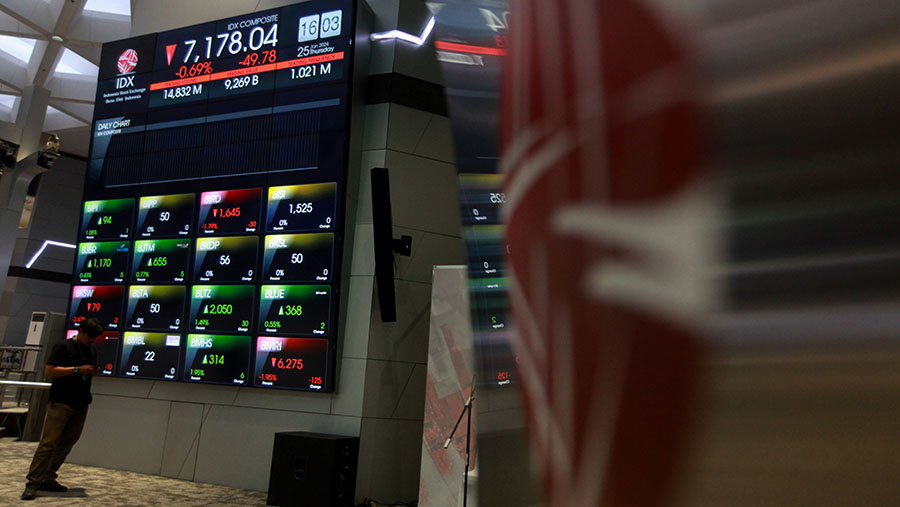 Karyawan melintas di depan layar pergerakan perdagangan saham (IHSG) di Bursa Efek Indonesia (BEI). (Bloomberg Technoz/Andrean Kristianto)