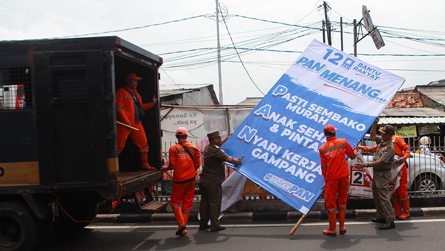 Petugas gabungan menertibkan alat peraga kampanye (APK) di Jalan Kramat Jati, Senin (29/1/2024). (Bloomberg Technoz/Andrean Kristianto)