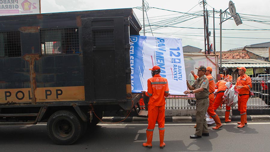 Petufgas gabungan menertibkan alat peraga kampanye (APK) di Jalan Kramat Jati, Senin (29/1/2024). (Bloomberg Technoz/Andrean Kristianto)