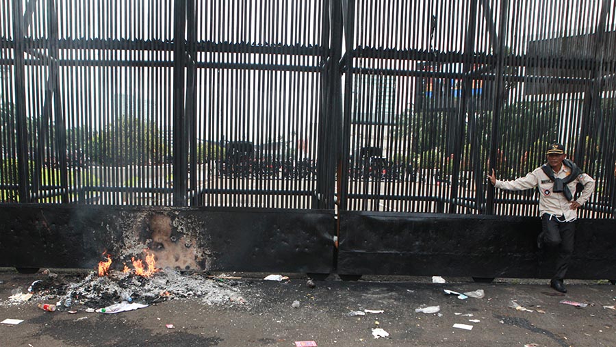 Massa aparat desa dari Apdesi juga sempat membakar kertas di depan pagar gedung DPR. (Bloomberg Technoz/Andrean Kristianto)