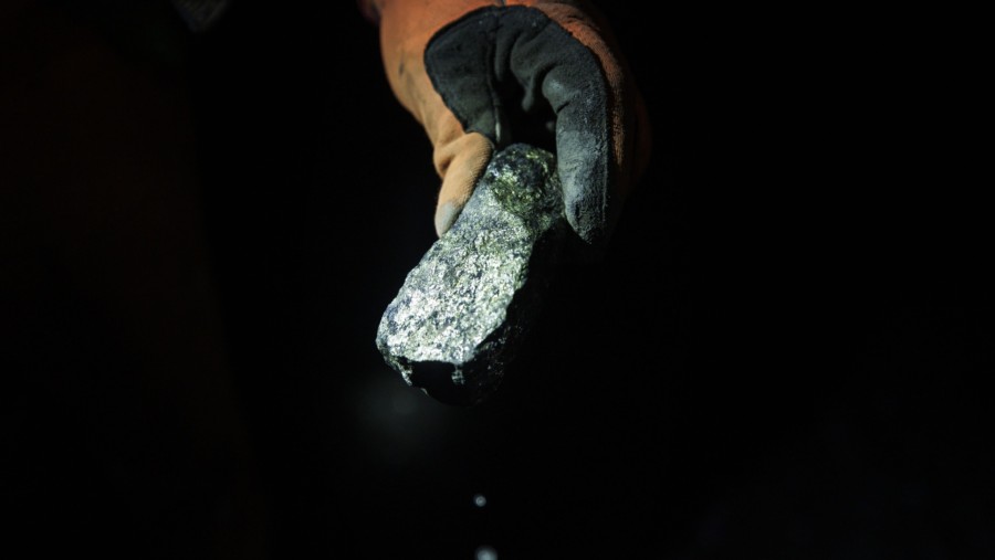 Seorang pekerja memegang sepotong bijih dengan campuran mineral dan logam di tambang./Bloomberg-Cole Burston