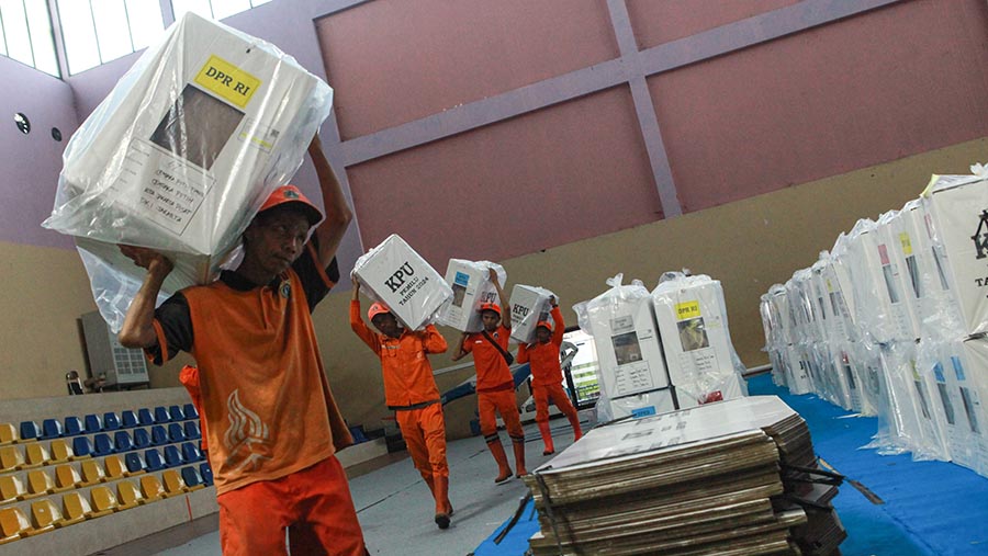 Petugas PPSU mengangkat logistik pemungutan suara di GOR Cempaka Putih, Jakarta, Selasa (13/2/2023). (Bloomberg Technoz/Andrean Kristianto)