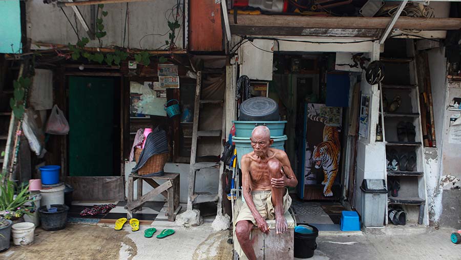 Warga duduk di depan rumahnya di pemukiman kawasan Pejompongan, Jakarta, Kamis (22/2/2024). (Bloomberg Technoz/Andrean Kristianto)