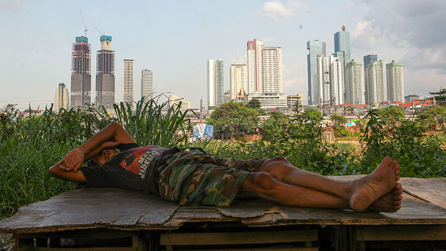 Warga tidur dengan latar gedung bertingkat di Jakarta, Kamis (22/2/2024). (Bloomberg Technoz/Andrean Kristianto)