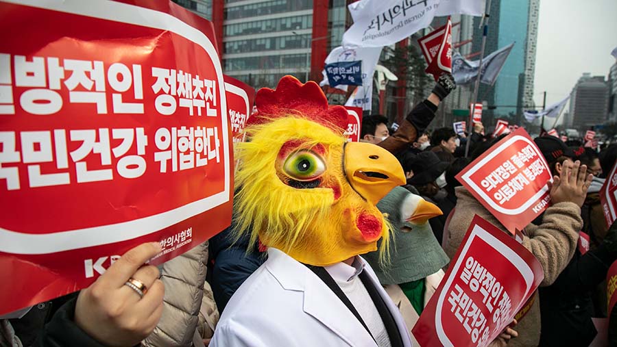 Peserta aksi, mengenakan masker dan memegang spanduk, menuntut pembatalan rencana pemerintah. (Jean Chung/Bloomberg)