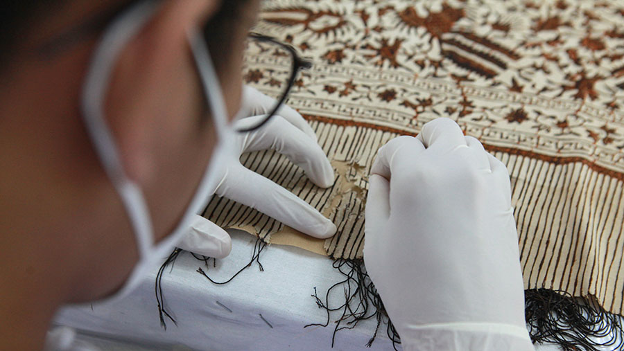 Petugas Pusat Konservasi Cagar Budaya melakukan perawatan koleksi Museum Tekstil di Jakarta, Selasa (5/3/2024). (Bloomberg Technoz/Andrean Kristianto)