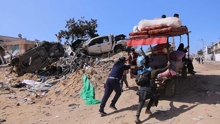 Warga Palestina mendorong gerobak berisi barang mereka pasca serangan Israel di Khan Younis, Gaza selatan (8/3/2024). (Ahmad Salem/Bloomberg)