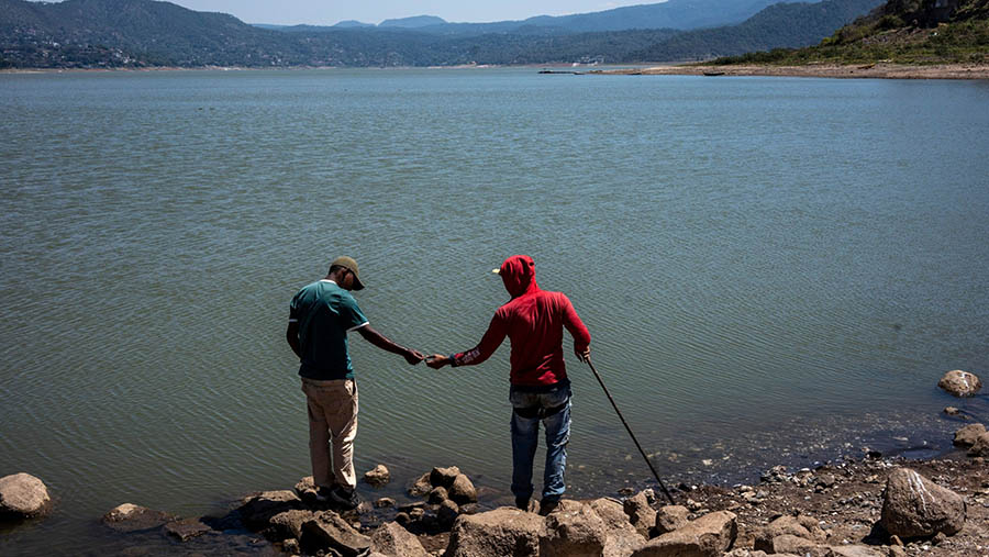Dua warga melihat ketinggian air di bendungan Miguel Aleman yang mengering di Valle de Bravo, Meksiko, Senin (11/3/2024). (Cesar Rodriguez/Bloomberg)