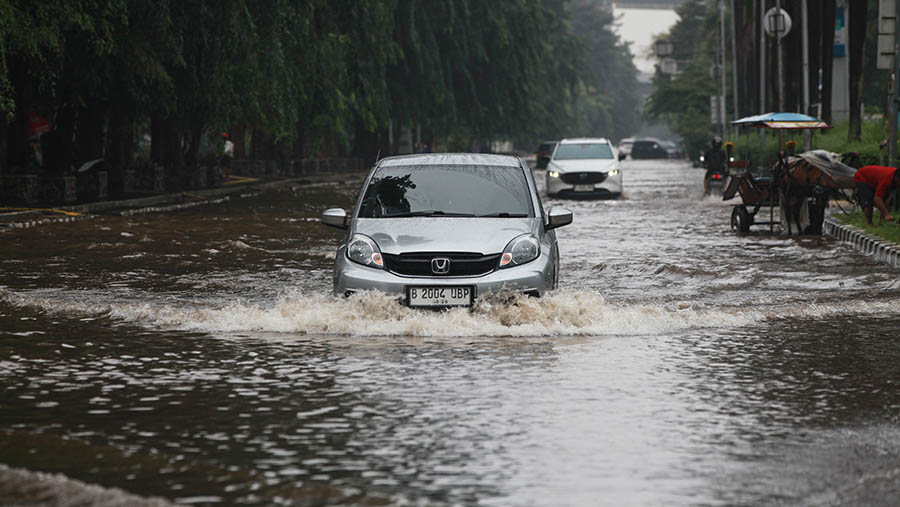 Beberapa mobil masih nekat untuk menerobos banjir tersebut. (Bloomberg Technoz/Andrean Kristianto)