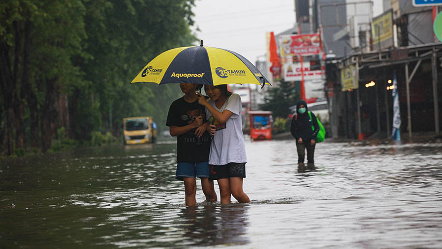 Warga melintasi banjir di kawasan Kelapa Gading, Jakarta Utara, Jumat (22/3/2024). (Bloomberg Technoz/Andrean Kristianto)
