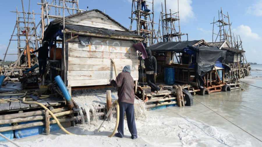 Para pekerja mengoperasikan rakit kayu untuk mengeruk bijih timah di lepas pantai Pulau Bangka./Bloomberg-Dimas Ardian