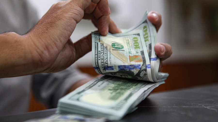 Pekerja menghitung dolar AS di salah satu gerai penukaran uang asing di Jakarta, Senin (1/4/2024). (Bloomberg Technoz/Andrean Kristianto)