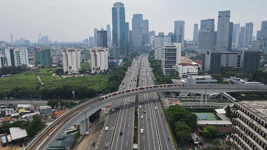 Kereta LRT Jabodebek melintas di kawasan Gatot Subroto dengan latar gedung di Jakarta, Senin (8/4/2024). (Bloomberg Technoz/Andrean Kristianto)