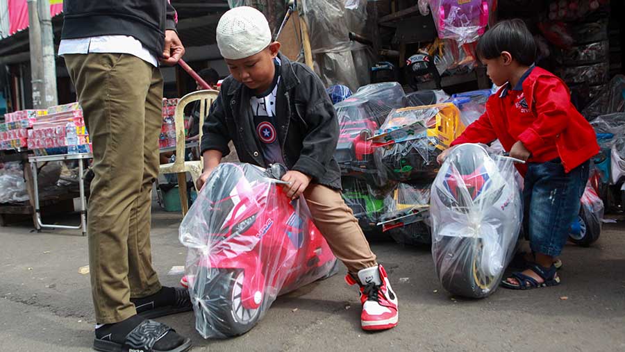 Dua anak mencoba mainan yang dijual di Pasar Gembrong, Jakarta, Kamis (11/4/2024). (Bloomberg Technoz/Andrean Kristianto)