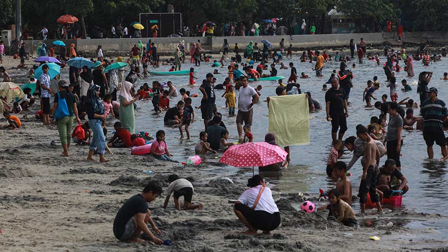 Pengunjung bermain di Pantai Lagoon Ancol, Jakarta, Jumat (12/4/2024). (Bloomberg Technoz/Andrean Kristianto)