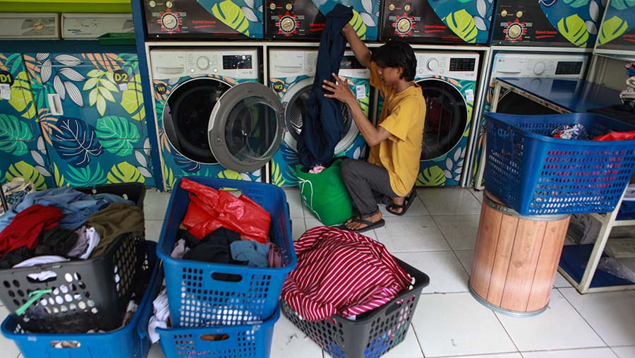 Pekerja memncuci pakaian pelanggan di tempat jasa pencucian pakaian di Pejaten, Jakarta, Selasa (6/4/2024). (Bloomberg Technoz/Andrean Kristianto)