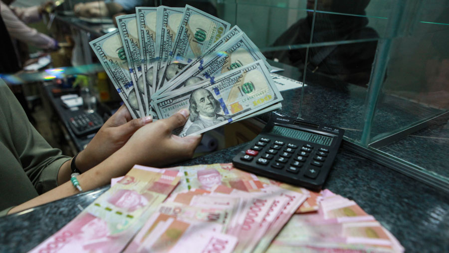 Pekerja merapihkan uang dolar AS dan rupiah di gerai penukaran uang di ITC Kuningan, Jakarta, Rabu (17/4/2024). (Bloomberg Technoz/Andrean Kristianto)