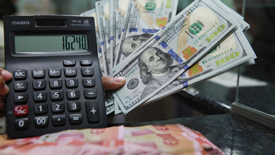 Pekerja merapihkan uang dolar AS dan rupiah di gerai penukaran uang di ITC Kuningan, Jakarta, Rabu (17/4/2024). (Bloomberg Technoz/Andrean Kristianto)