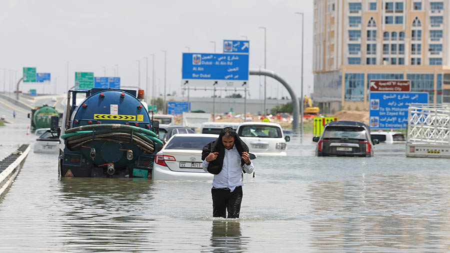 Seorang pengemudi berjalan melewati banjir setelah hujan badai di Dubai, Uni Emirat Arab, Selasa (16/4/2024). (Christopher Pike/Bloomberg)
