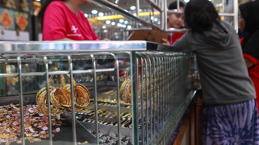 Karyawan melayani jual beli emas perhiasan di sebuah toko emas di Pasar Kebayoran, Jakarta, Jumat (19/4/2024). (Bloomberg Technoz/Andran Kristianto)