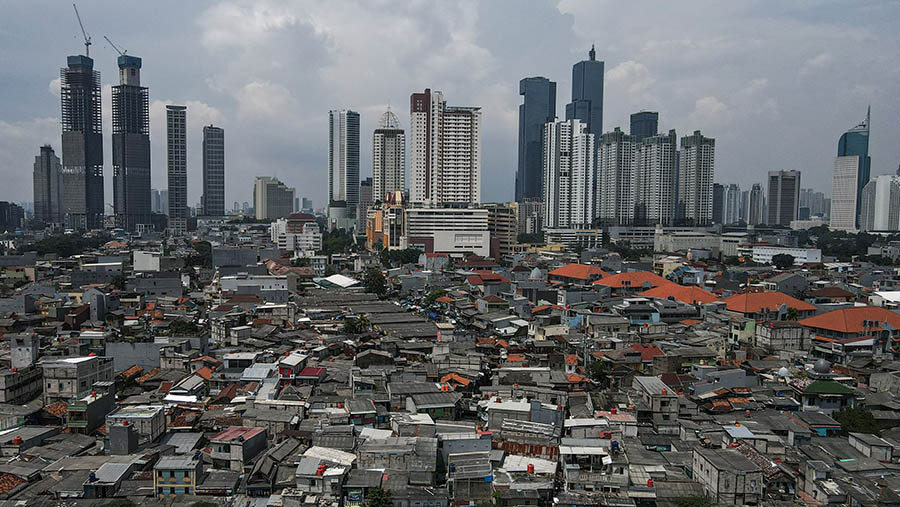 Suasana pemukiman dengan latar gedung bertingkat di Jakarta, Selasa (24/4/2024). (Bloomberg Technoz/Andrean Kristianto)