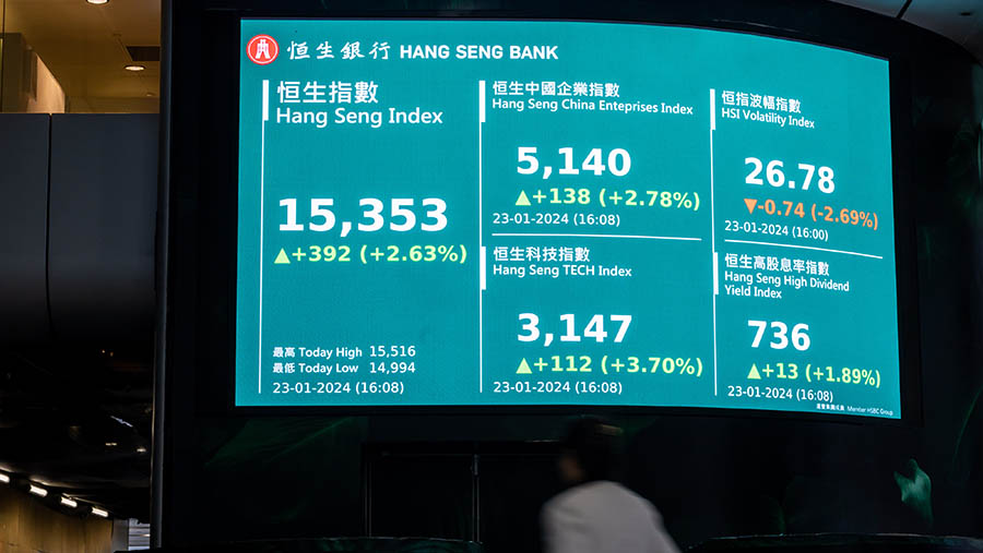 Warga melintas di depan layar Indeks Hang Seng di Hong Kong, Tiongkok, Selasa (23/1/2024). (Paul Yeung/Bloomberg)