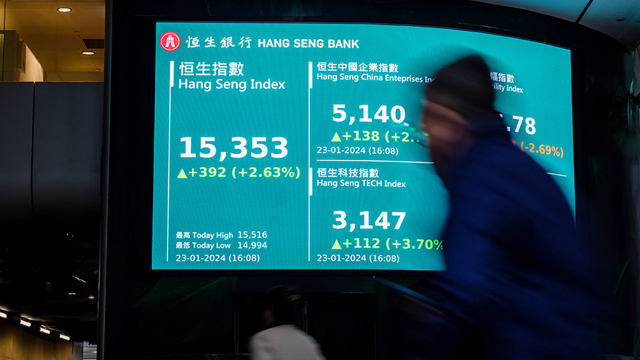Warga melintas di depan layar Indeks Hang Seng di Hong Kong, Tiongkok, Selasa (23/1/2024). (Paul Yeung/Bloomberg)