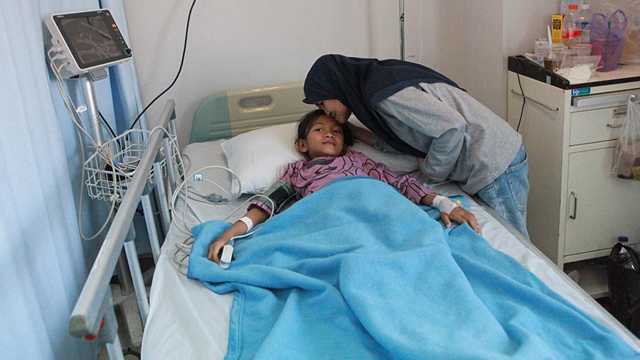 Orang tua mencium anaknya yang dirawat karena demam berdarah dengue (DBD) di RSUD Tamansari, Jumat (26/4/2024). (Bloomberg Technoz/Andrean Kristianto)