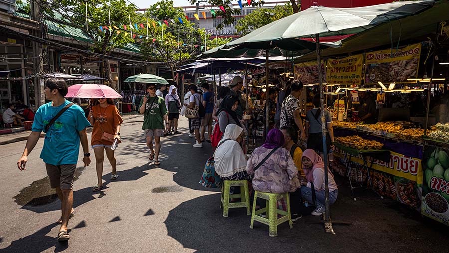 Pejalan kaki menggunakan payung saat suhu tinggi di Pasar Chatuchak, Bangkok, Thailand, Minggu (28/4/2024). (Andre Malerba/Bloomberg)