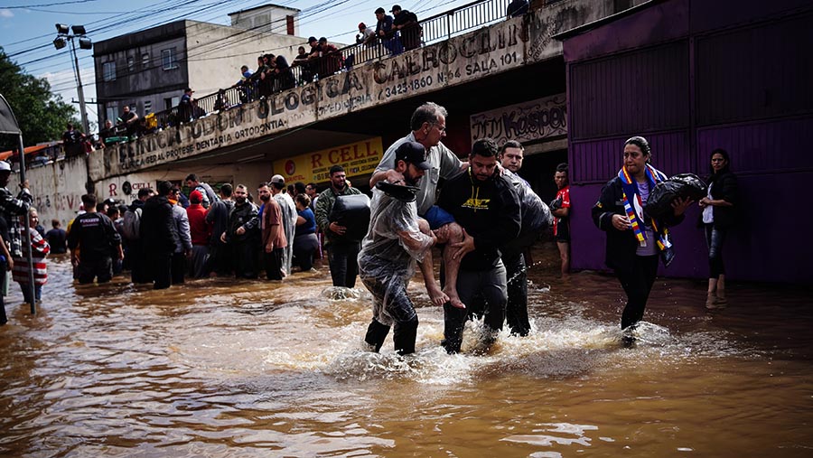 Warga dibantu relawan melewati banjir di Canoas, Rio Grande do Sul, Brasil, Minggu (5/5/2024). (Carlos Macedo/Bloomberg)