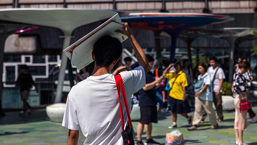 A man uses cardboard paper to shade from the sun in Bangkok (Andre Malerba/Bloomberg)