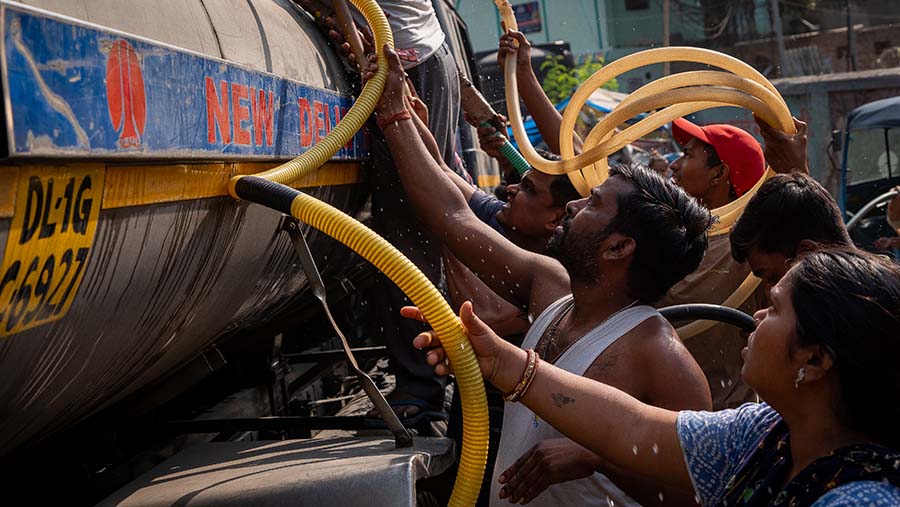 Warga berkumpul di sekitar mobil tangki untuk mengambil air saat suhu tinggi di New Delhi, India, Sabtu (18/5/204). (Anindito Mukherjee/Bloomberg)