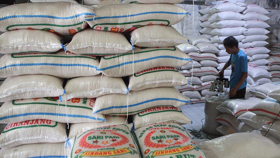 Pekerja merapihkan karung beras di agen beras kawasan Pamulang, Rabu (22/5/2024). (Bloomberg Technoz/ Andrean Kristianto)
