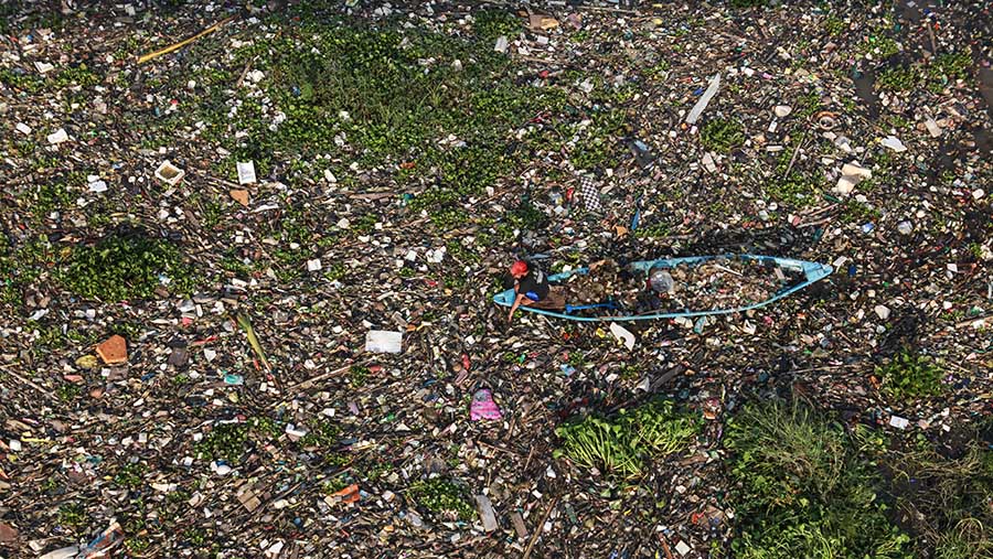 Warga mengambil sampah plastik di Sungai Citarum di Batujajar, Kab. Bandung, Jawa Barat, Kamis (13/6/2024). (Bloomberg Technoz/Andrean Kristianto)
