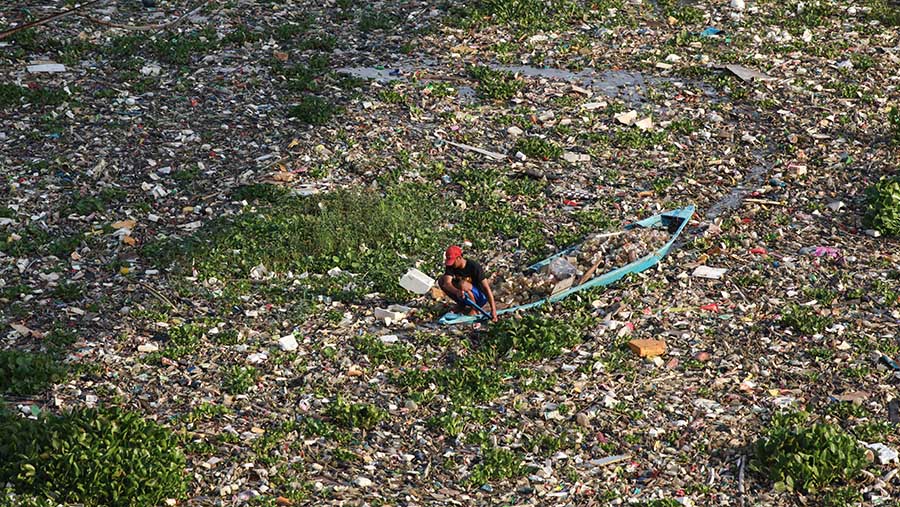 Warga mengambil sampah plastik di Sungai Citarum di Batujajar, Kab. Bandung, Jawa Barat, Kamis (13/6/2024). (Bloomberg Technoz/Andrean Kristianto)
