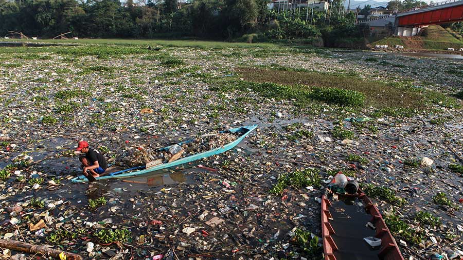 Warga mengambil sampah plastik di Sungai Citarum di Batujajar, Kab. Bandung, Jawa Barat, Kamis (13/6/2024). (Bloomberg Technoz/Andrean Kristianto)
