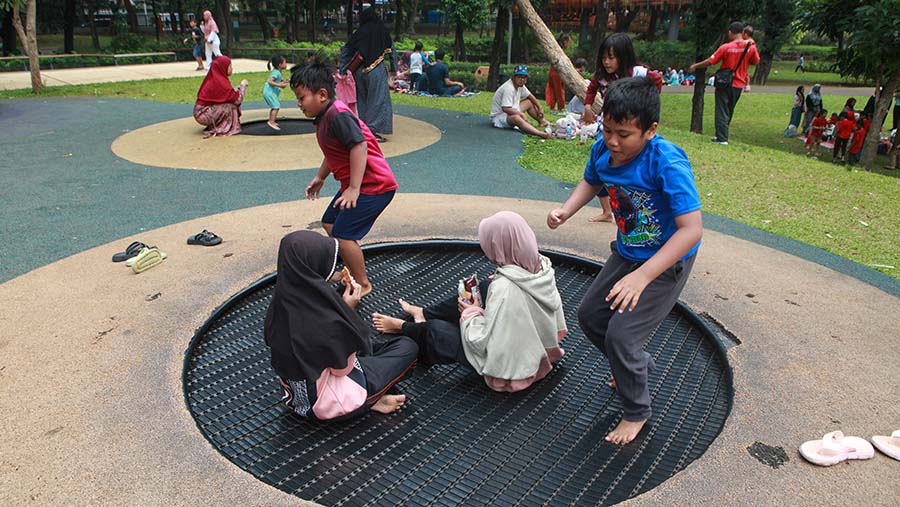 Sejumlah anak bermain di wahana yang tersedia di Tebet Eco Park, Jakarta, Selasa (18/6/2024). (Bloomberg Technoz/Andrean Kristianto)