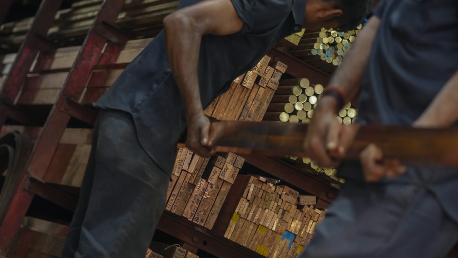 Pekerja menumpuk tembaga batangan./Bloomberg-Dhiraj Singh