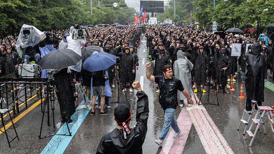 Pekerja berkumpul di tengah hujan lebat di luar salah satu kompleks pembuatan chip terbesar Samsung di selatan Seoul. (Jean Chung/Bloomberg)