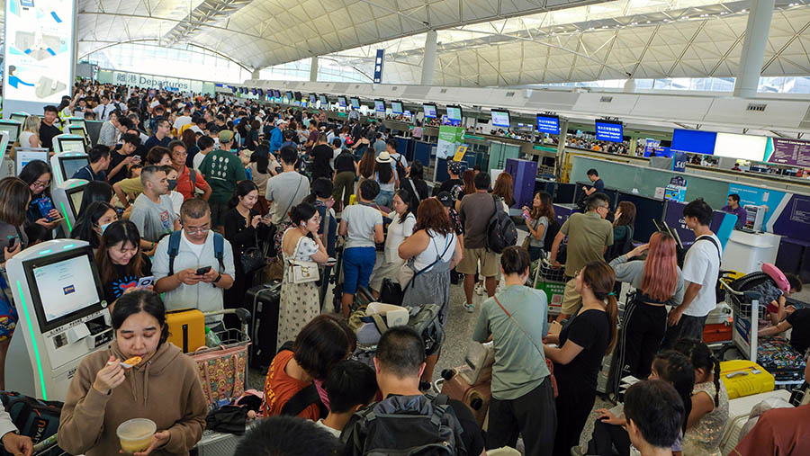 Penumpang mengantre di konter check-in Hong Kong Express Airways Ltd. di Bandara Internasional Hong Kong, Jumat (19/7/2024). (Yik Yeung-man/Bloomberg)